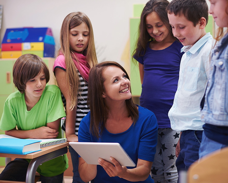 snapplify_cloud_services_pay_paragraph_image_2 - snapplify cloud services A teacher in a classroom, showing some children a Teacha! classroom resource on a tablet device